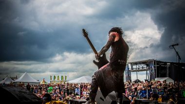 A man is playing a guitar on a stage in front of a crowd.