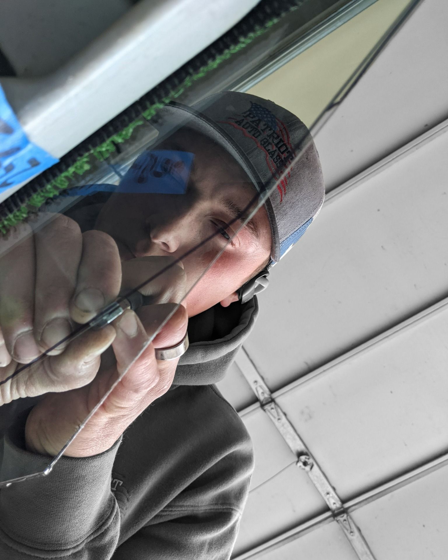 A man in a hat is holding a piece of glass in front of his face.