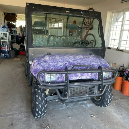A purple polaris vehicle is parked in a garage