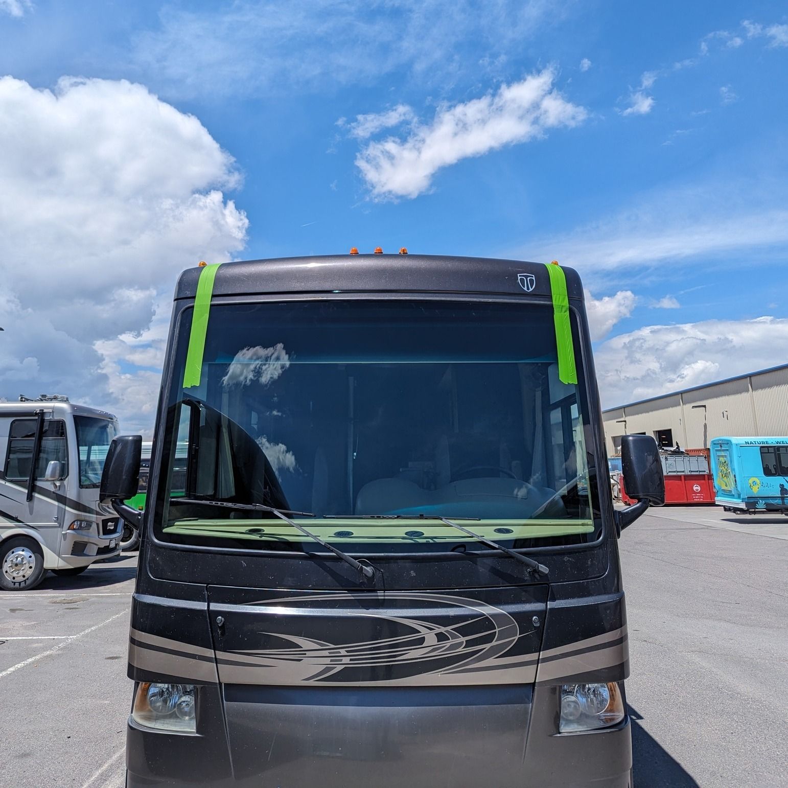 A black bus with green stripes on the front is parked in a parking lot.