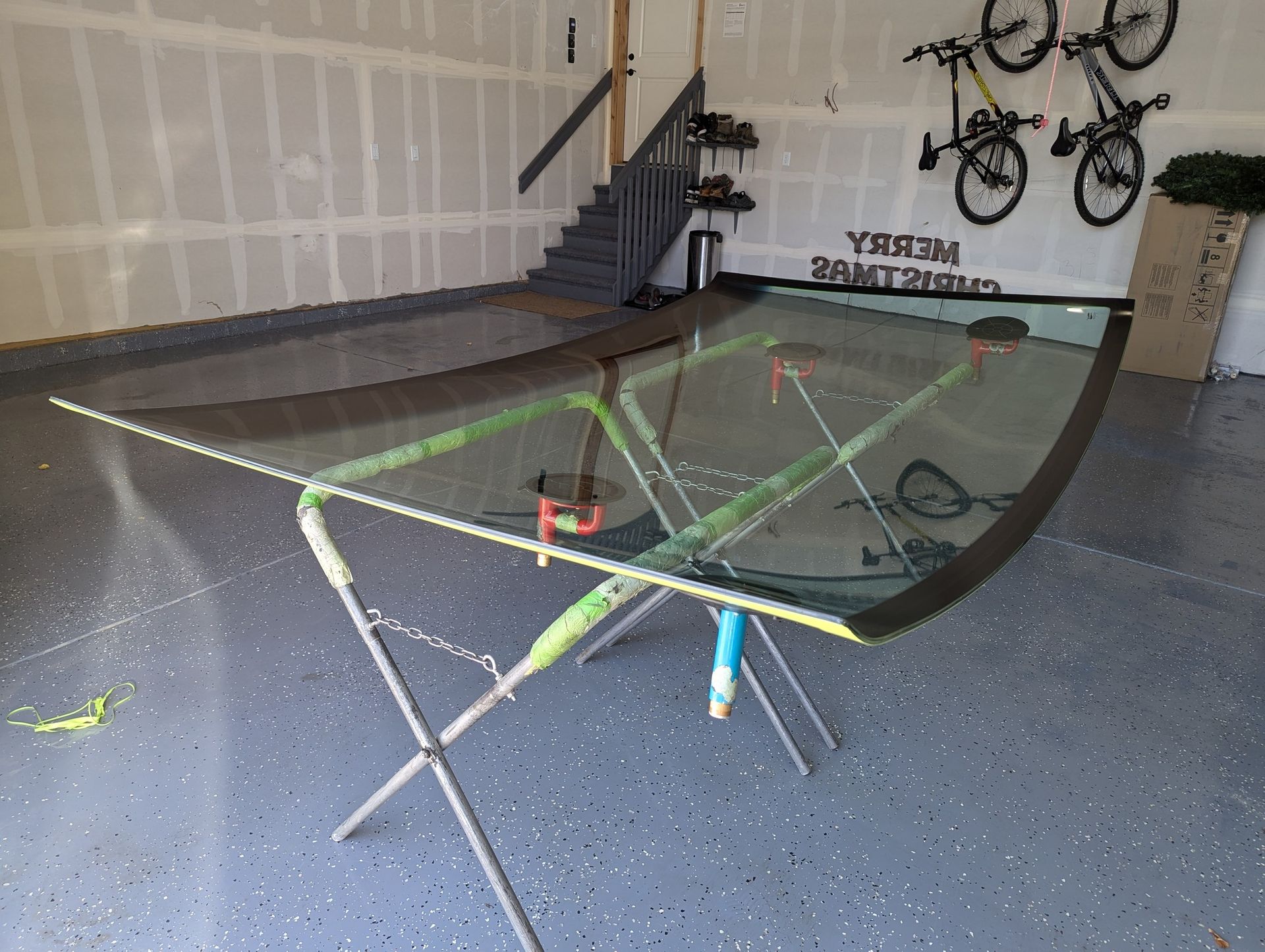 A windshield is sitting on a stand in a garage.