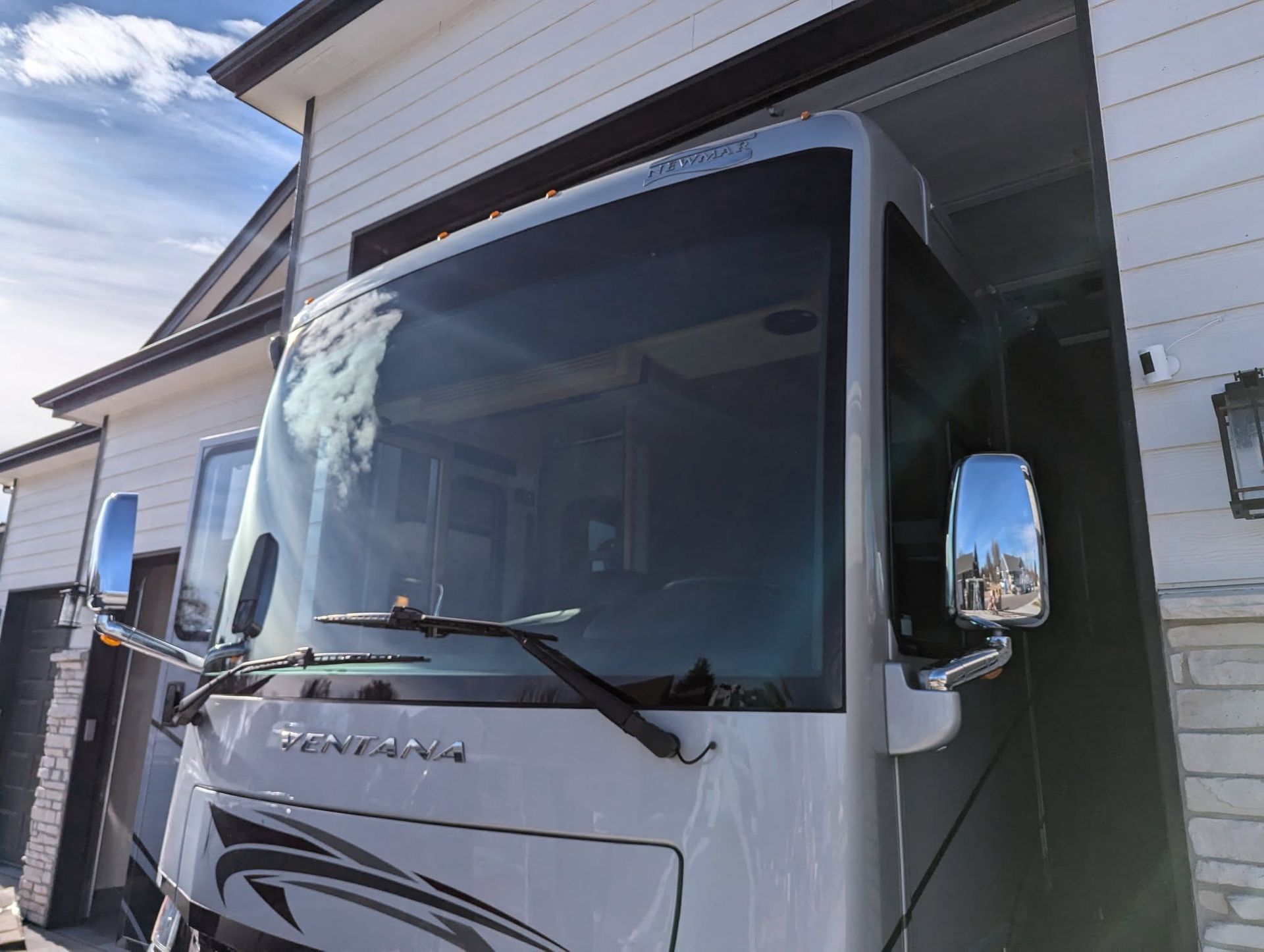 A white rv is parked in front of a garage.