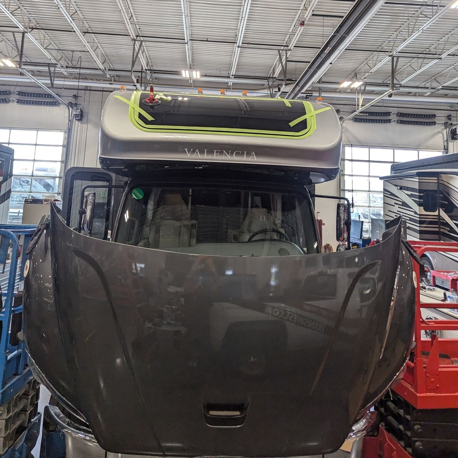 A truck with the hood up is sitting in a garage.