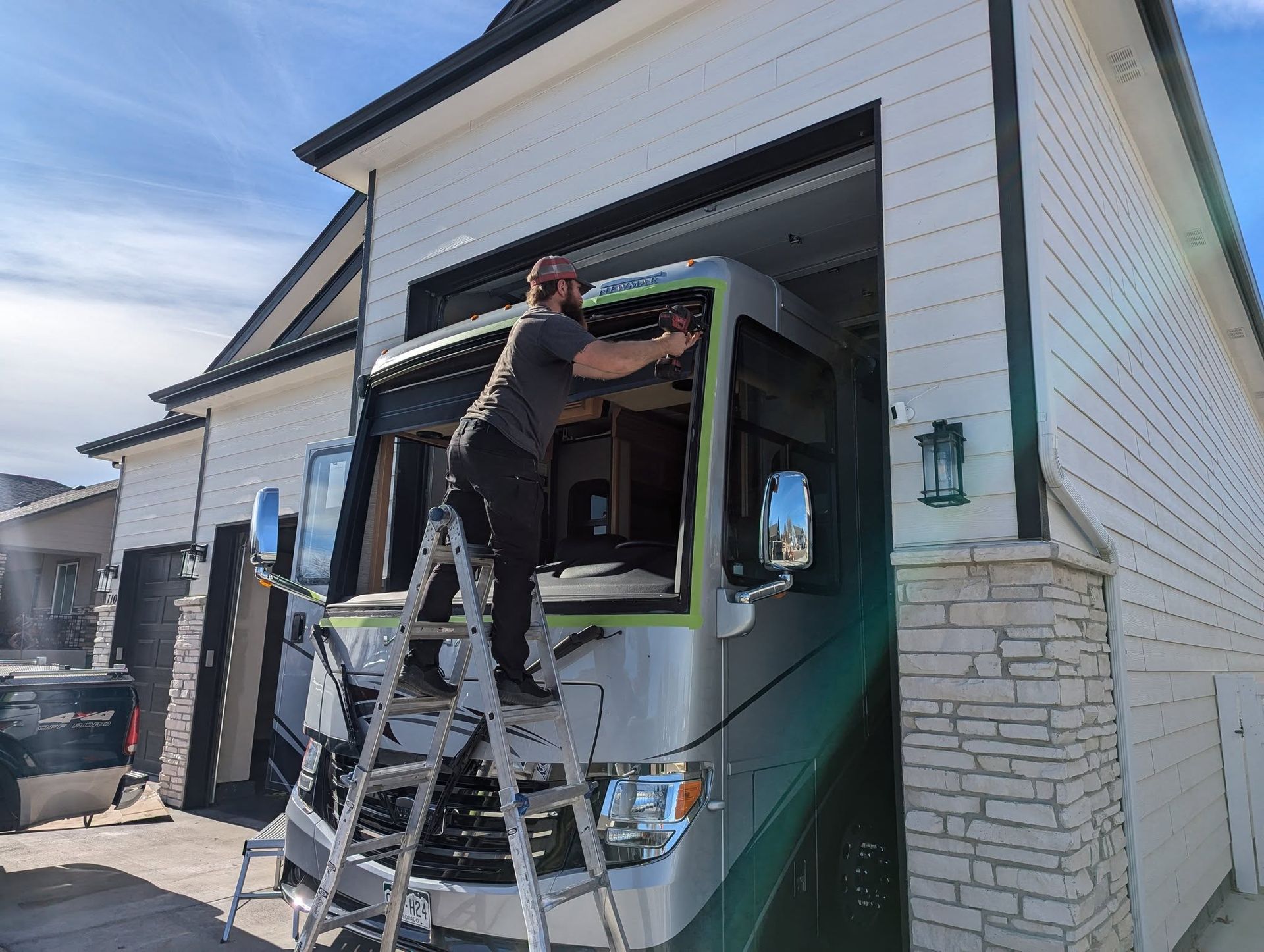 A man is standing on a ladder in front of a rv.