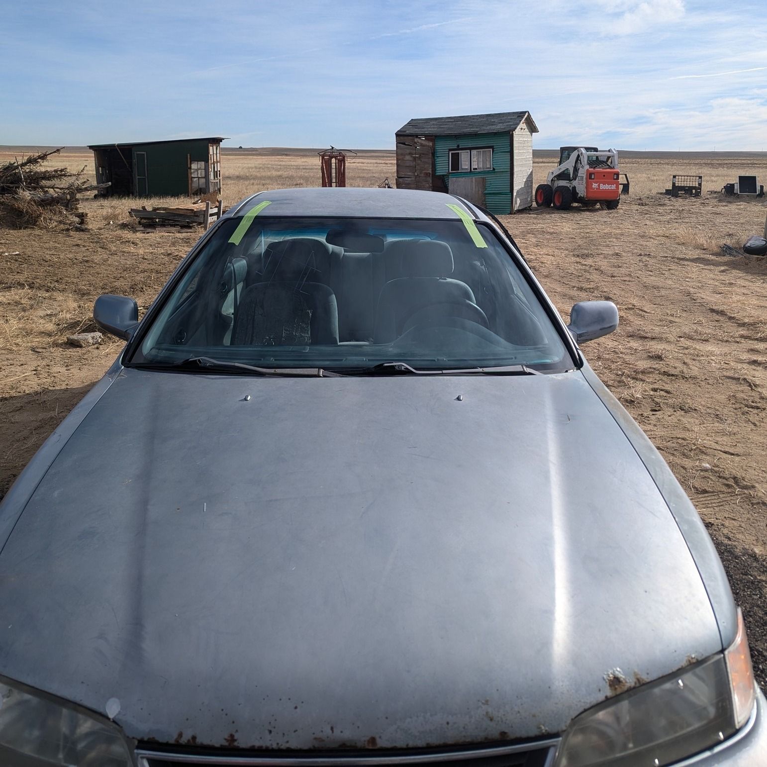 A silver car is parked in the middle of a desert