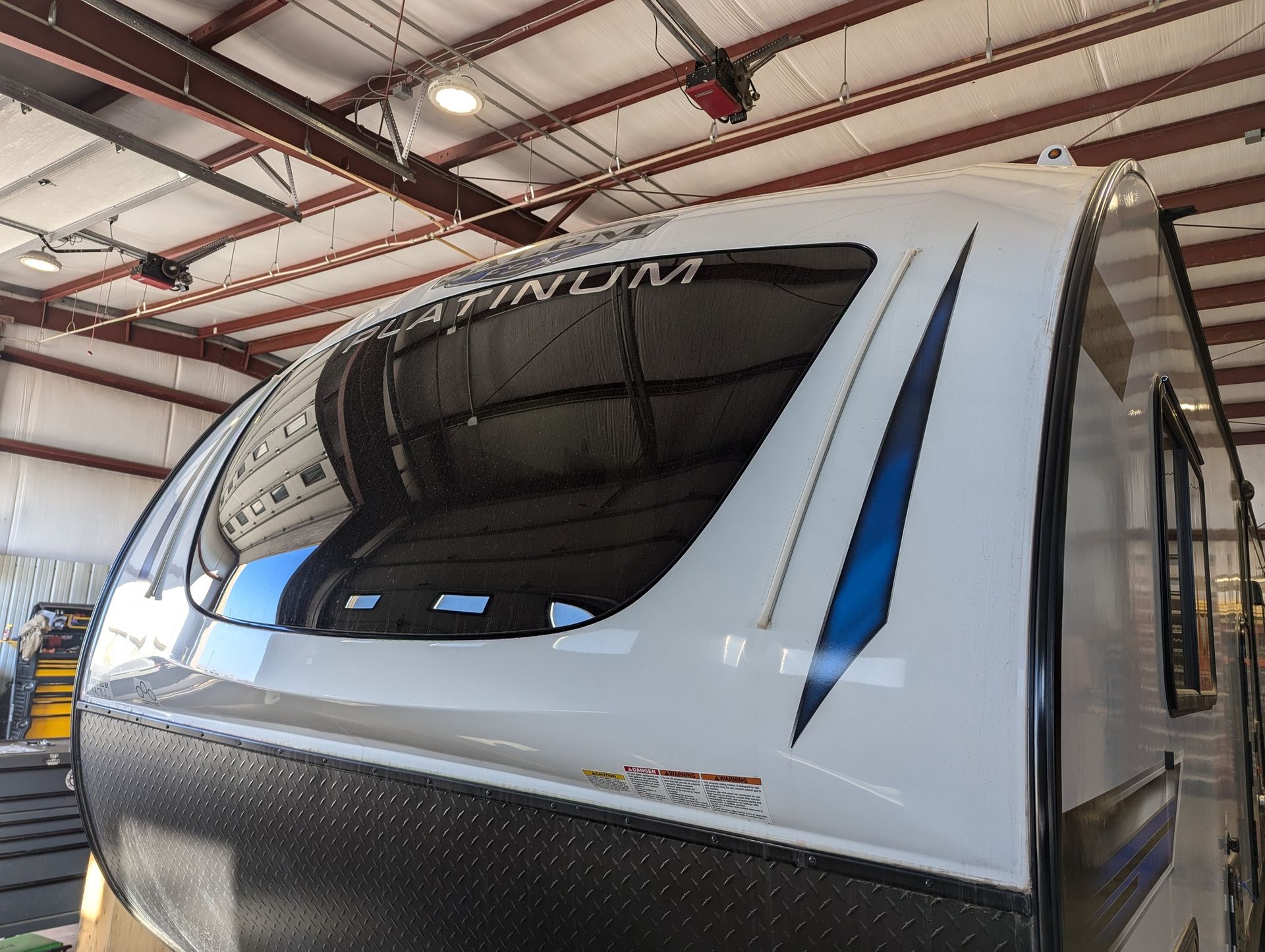 A white and black trailer is sitting in a garage.