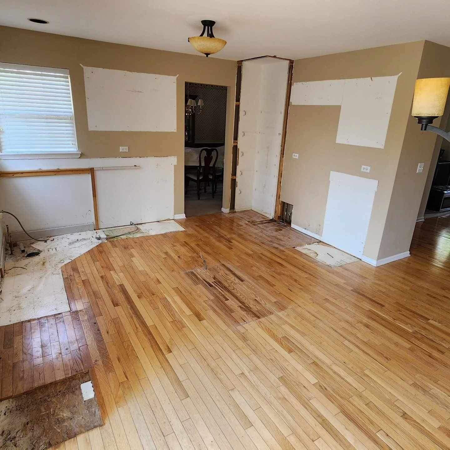Empty room with hardwood floor, white patchy walls, and a doorway to a closet or hall.