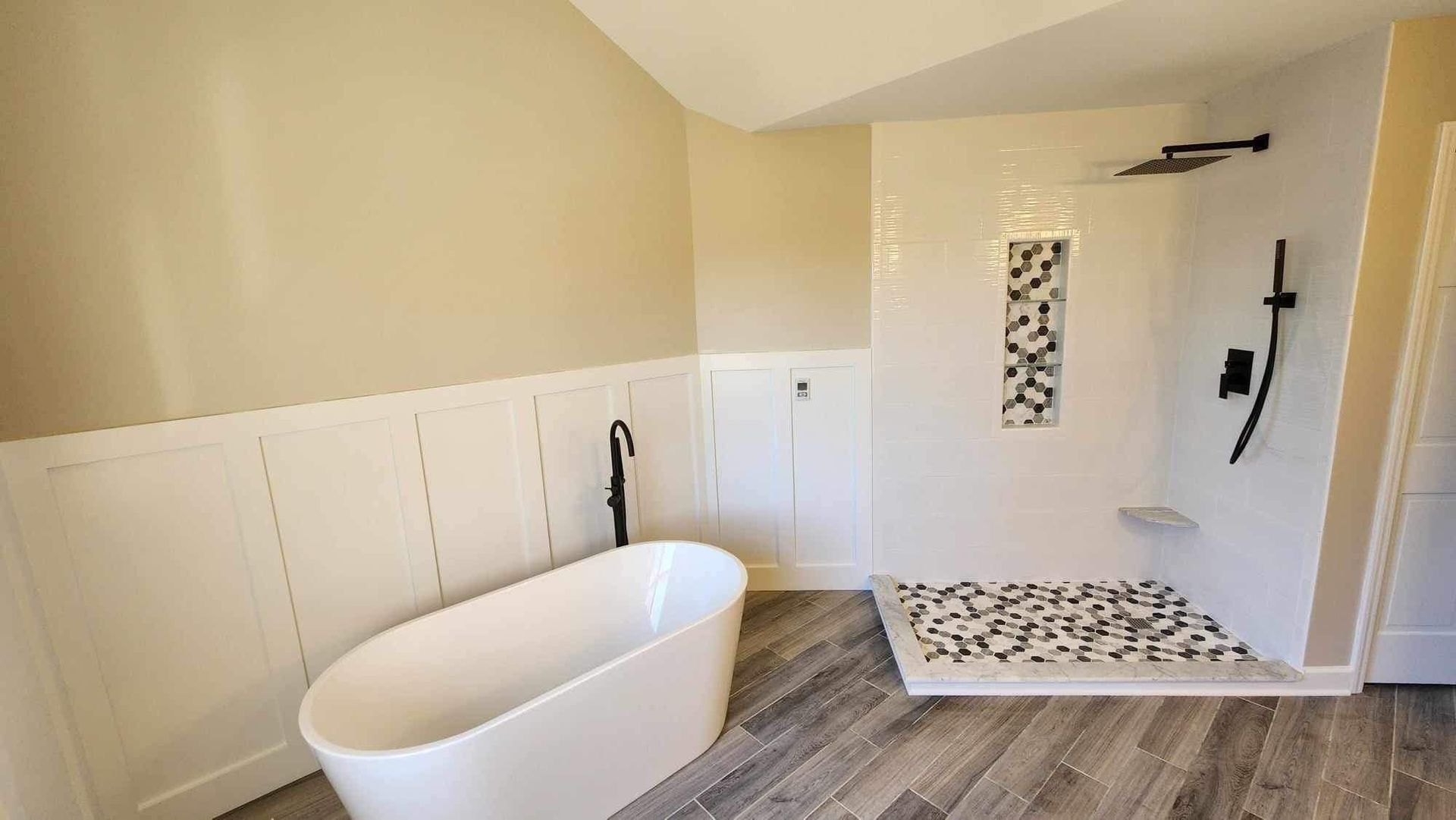Modern bathroom with a freestanding tub, tiled shower, and wood-look flooring