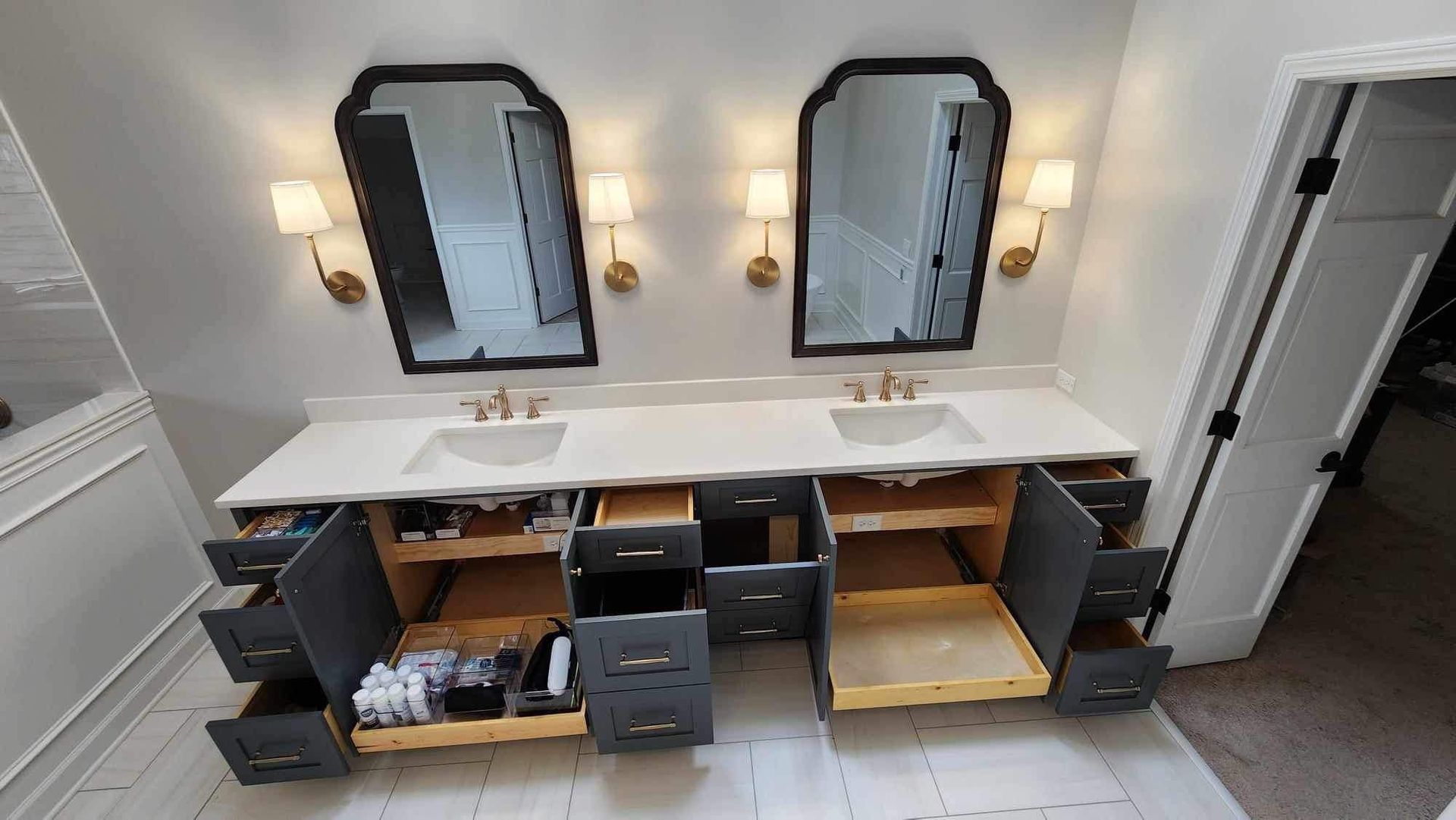 Double vanity bathroom with two mirrors, wall sconces, and open cabinets beneath a white countertop