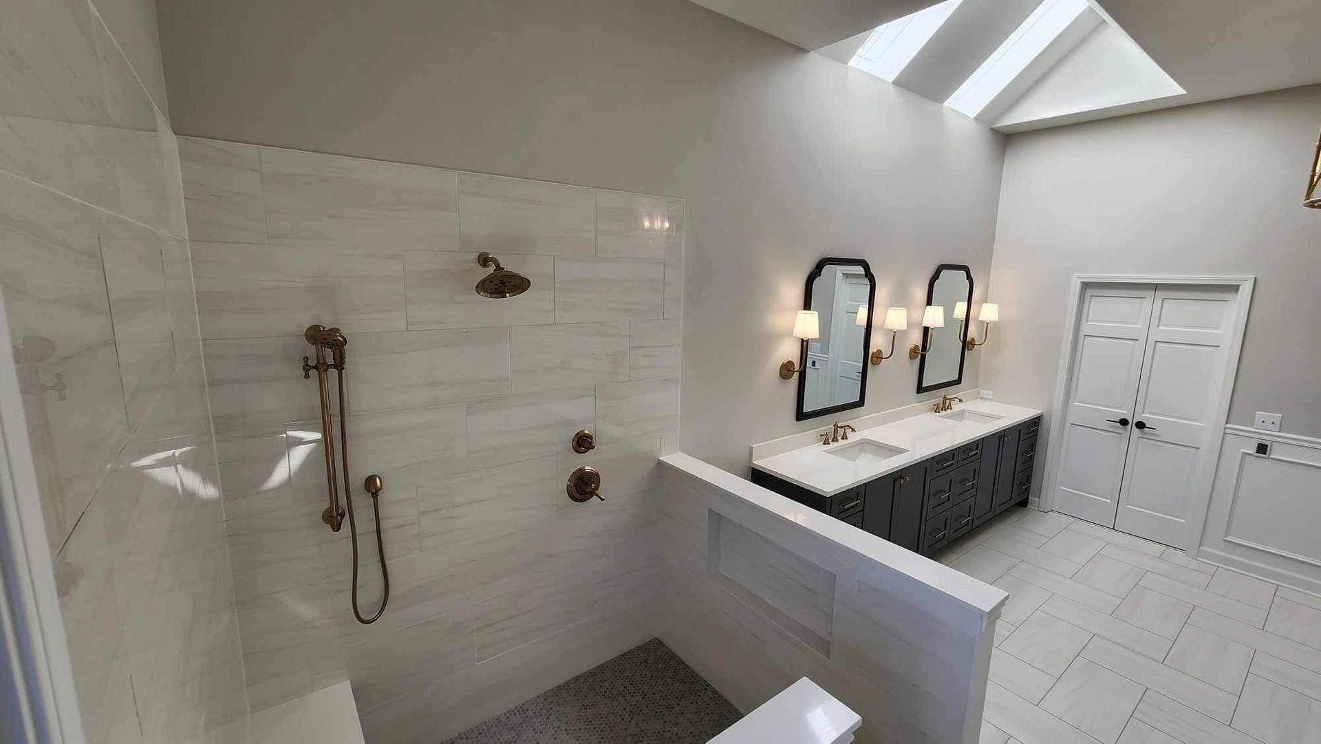 Bright white bathroom with walk-in shower, skylights, double vanity, and freestanding tub.
