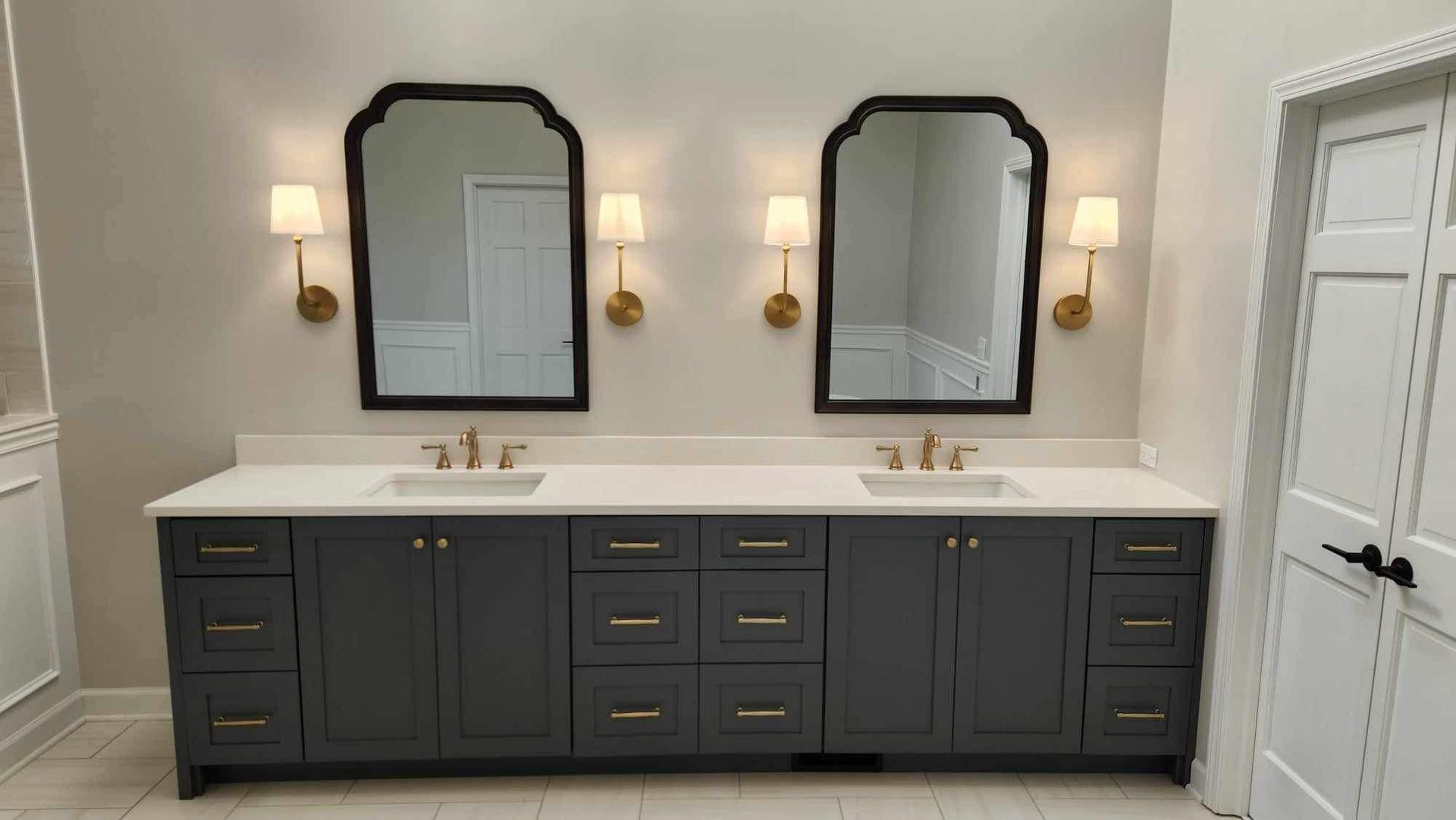 Double vanity bathroom with dark cabinets, white countertop, and two mirrors between wall sconces.