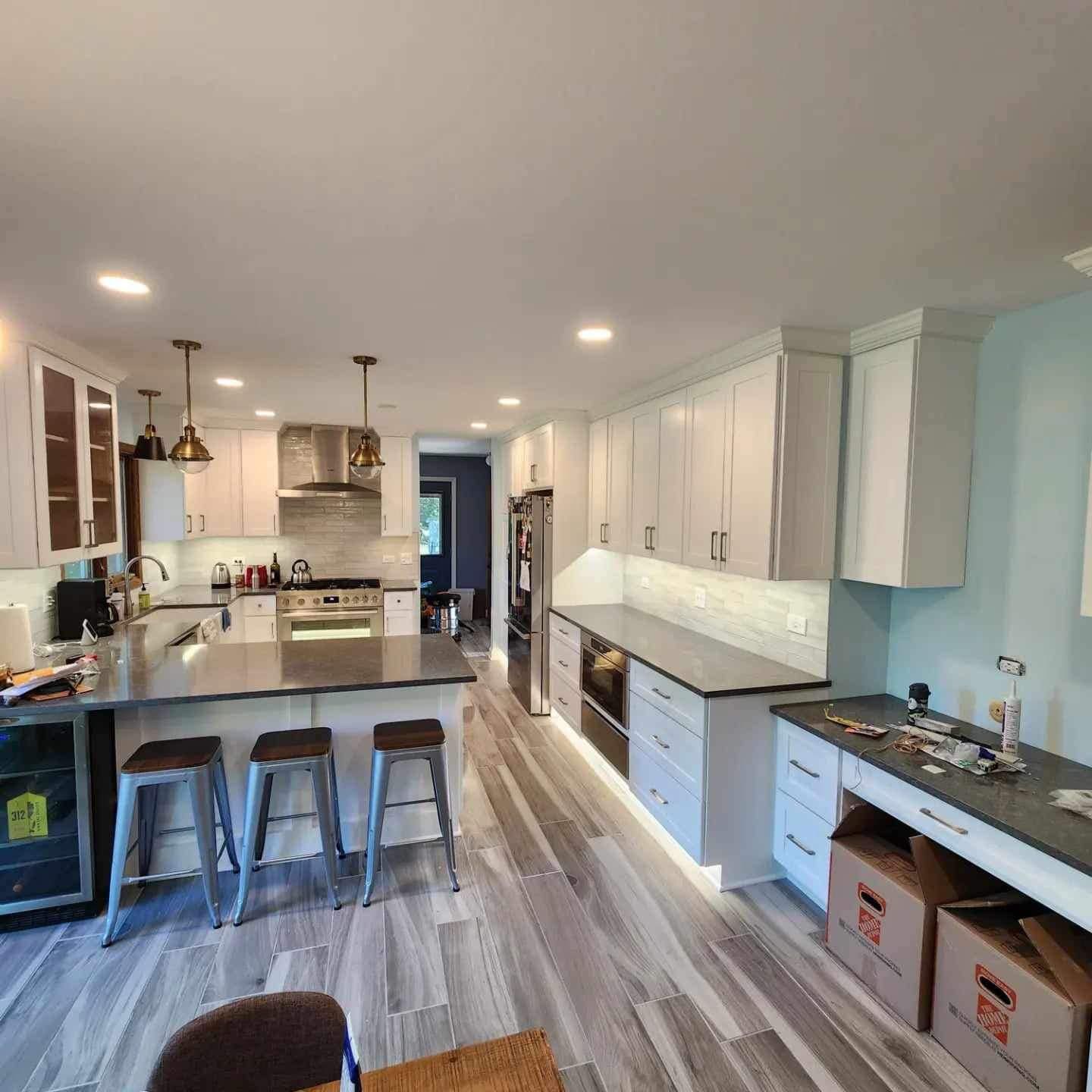 Bright modern kitchen with white cabinets, gray island, stools, and wood-look flooring