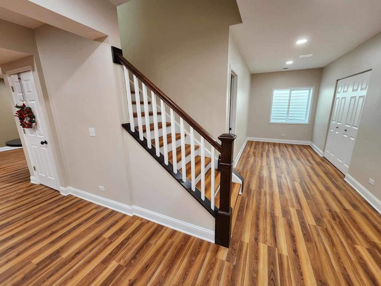 An interior room under renovation with exposed wooden ceiling beams, unfinished wall studs, and tools on a wooden floor.