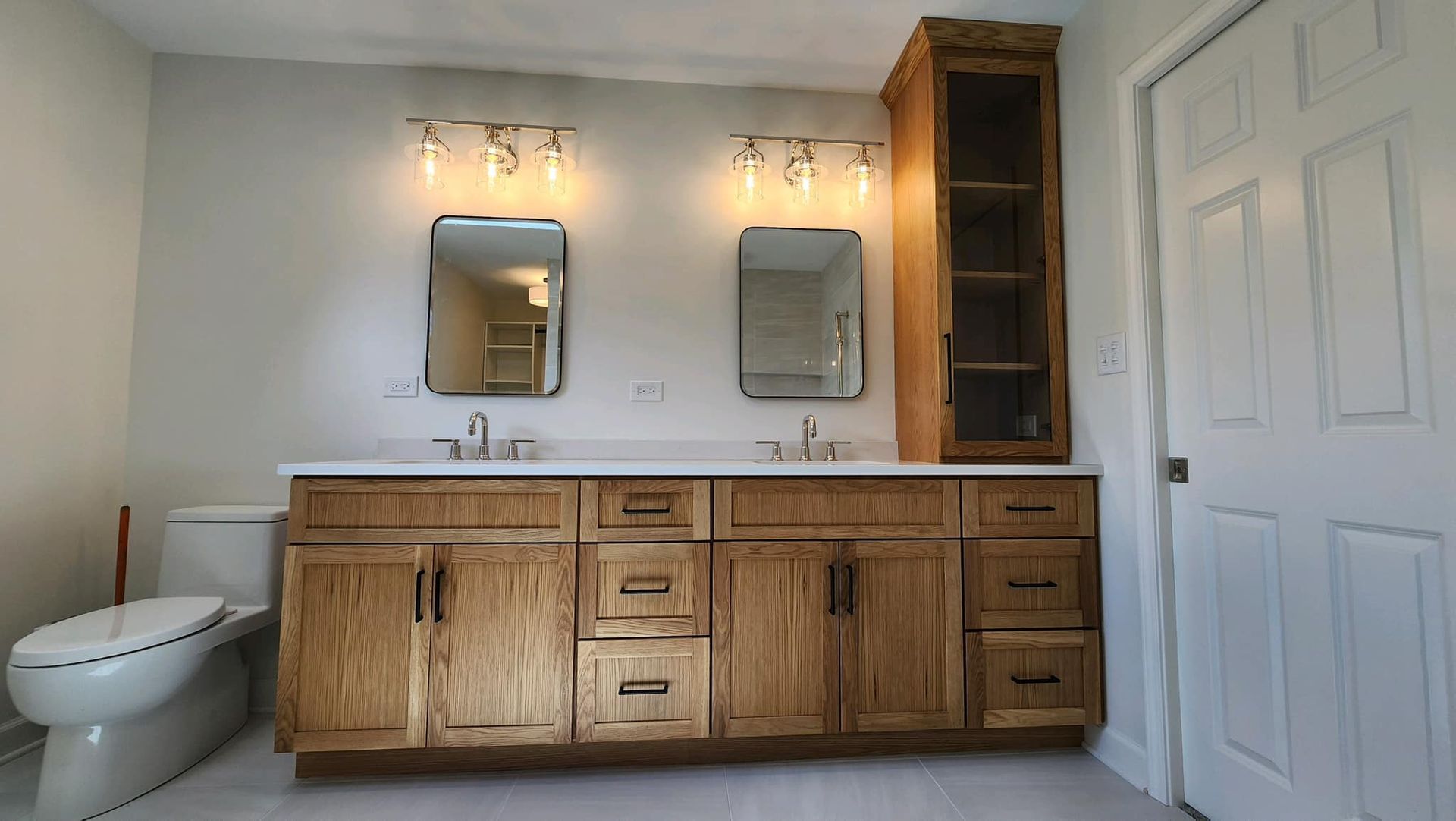 Rustic bathroom with wooden vanity, dual mirrors, wall lights, toilet, and white door