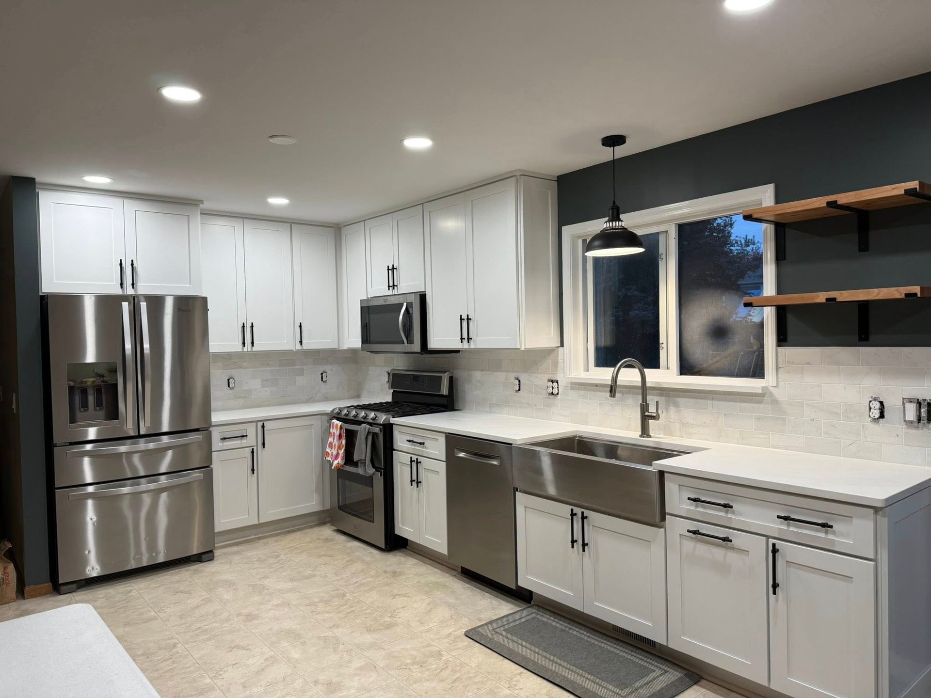 Modern white kitchen with stainless steel appliances, gray countertops, and pendant lights