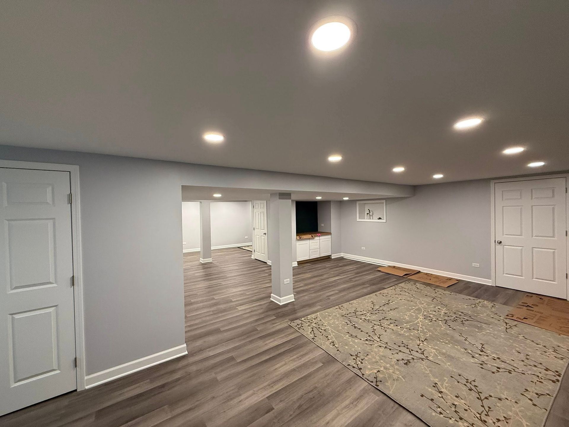 Empty finished basement with gray walls, recessed lights, wood flooring, carpet, and white doors