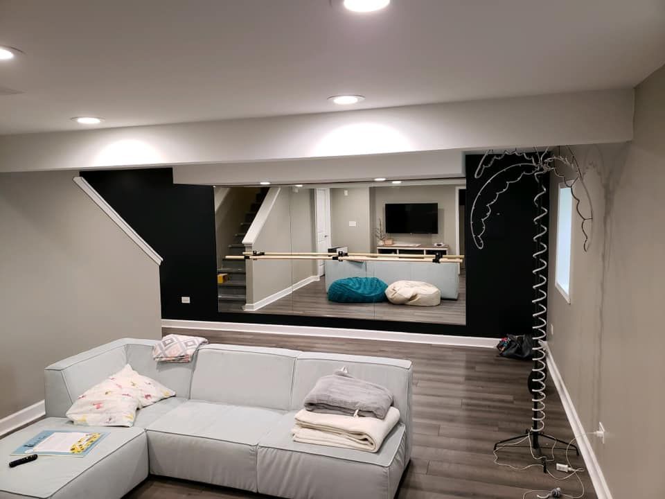 Living room with gray sectional sofa, wall mirror, and lounge area with teal beanbag in the background