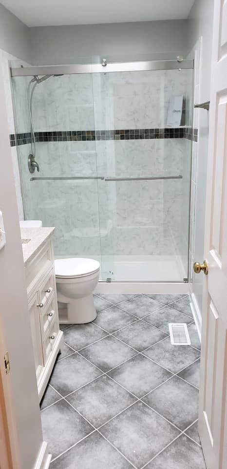 Small bathroom with glass shower, toilet, vanity, and gray tile floor