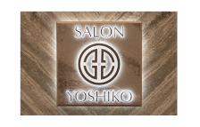 The logo for salon yoshiko is on a wooden wall.