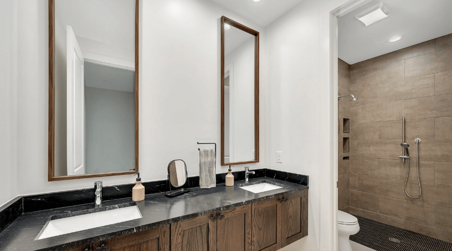 Two sink bathroom with tall mirrors and walk in shower