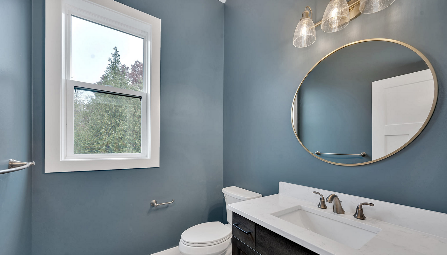 Bathroom painted soft blue with oval mirror