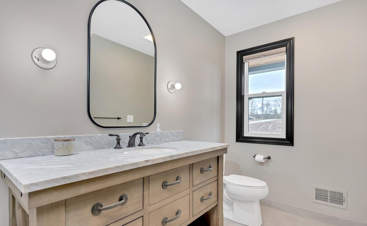 Bathroom with ornate built in sink cabinets and prominent framed mirror