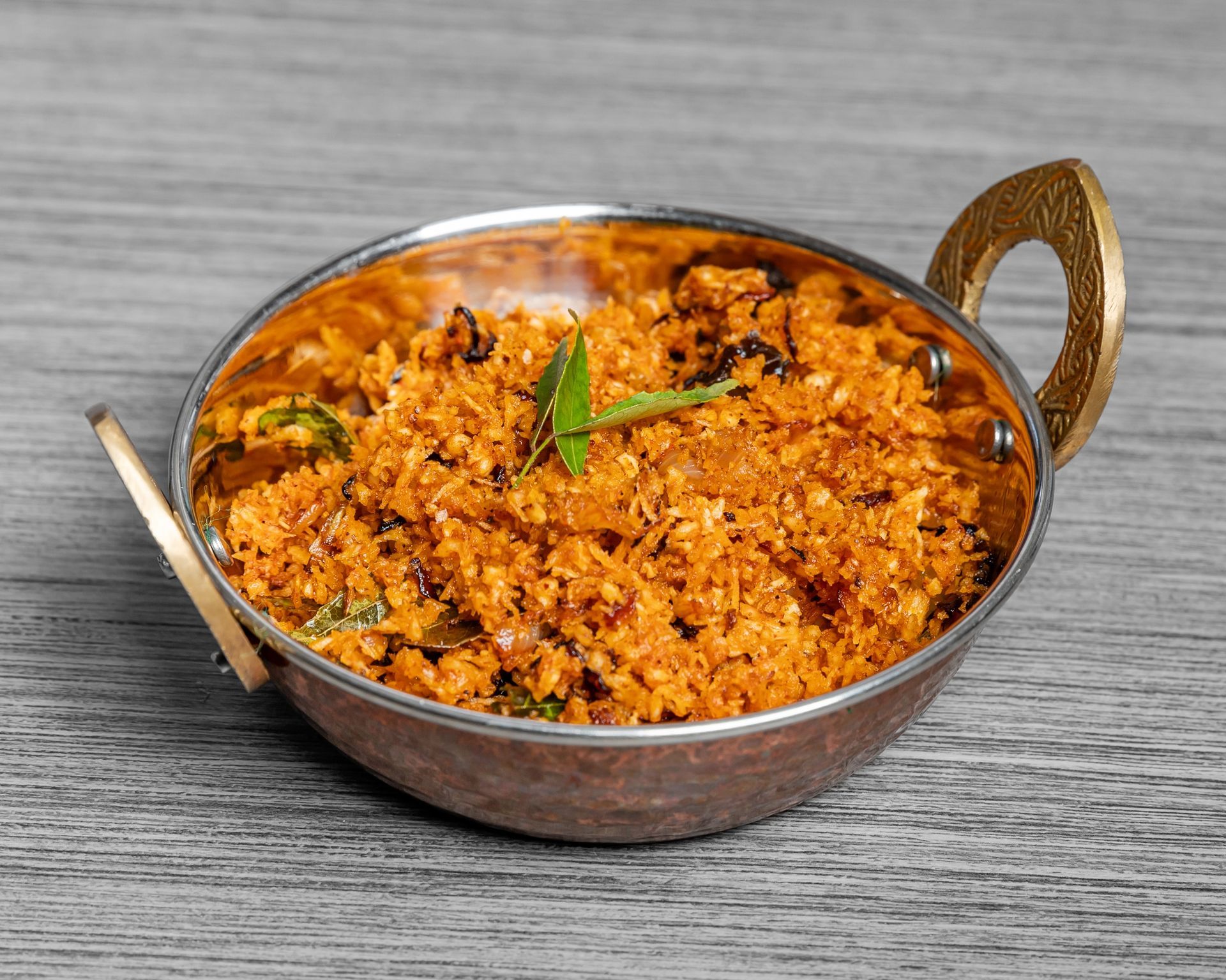 A bowl of coconut sambaal is sitting on a wooden table.