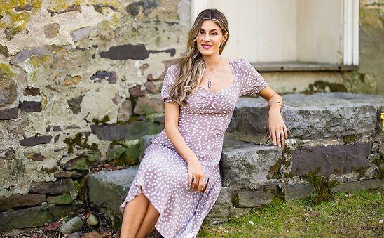 A woman in a purple dress is sitting on a set of stone steps.