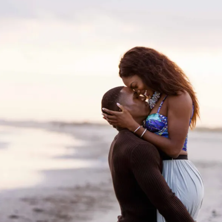 A man is kissing a woman on the forehead on the beach