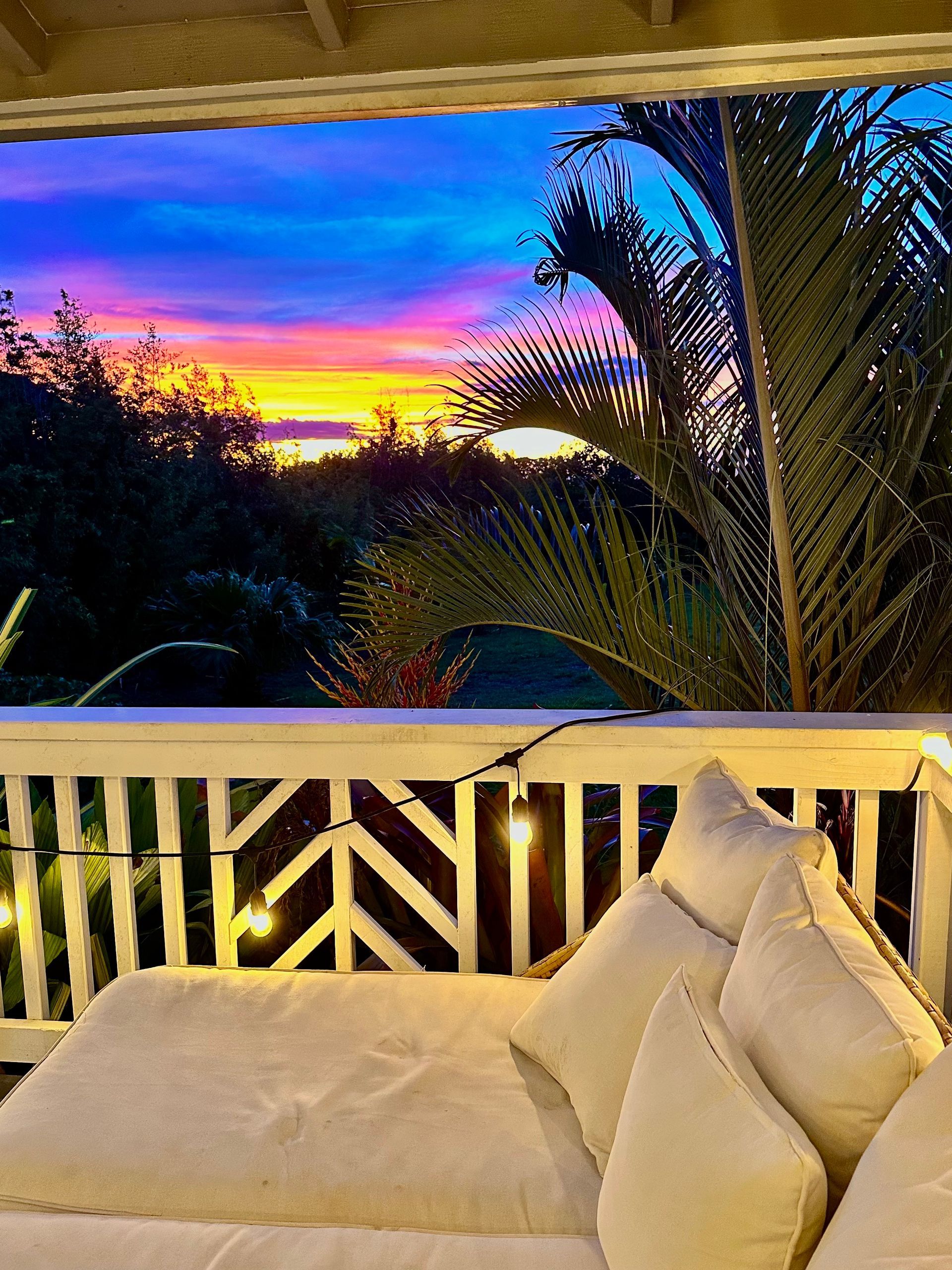 A balcony with a view of a sunset and palm trees