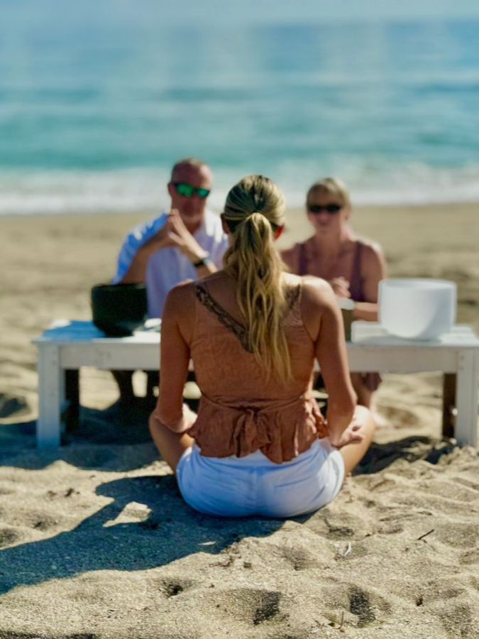 A man and a woman are walking on the beach holding hands.
