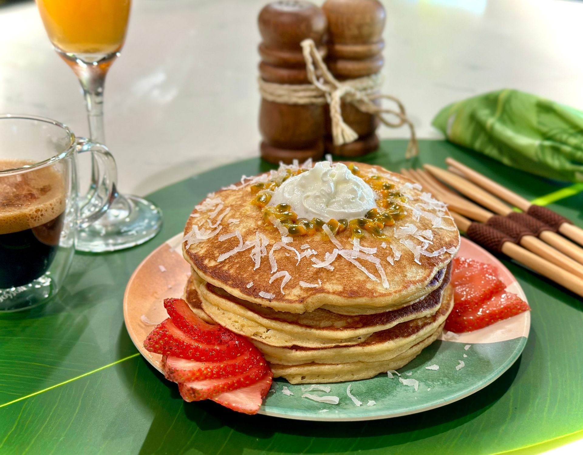 A stack of pancakes with whipped cream and strawberries on a plate.