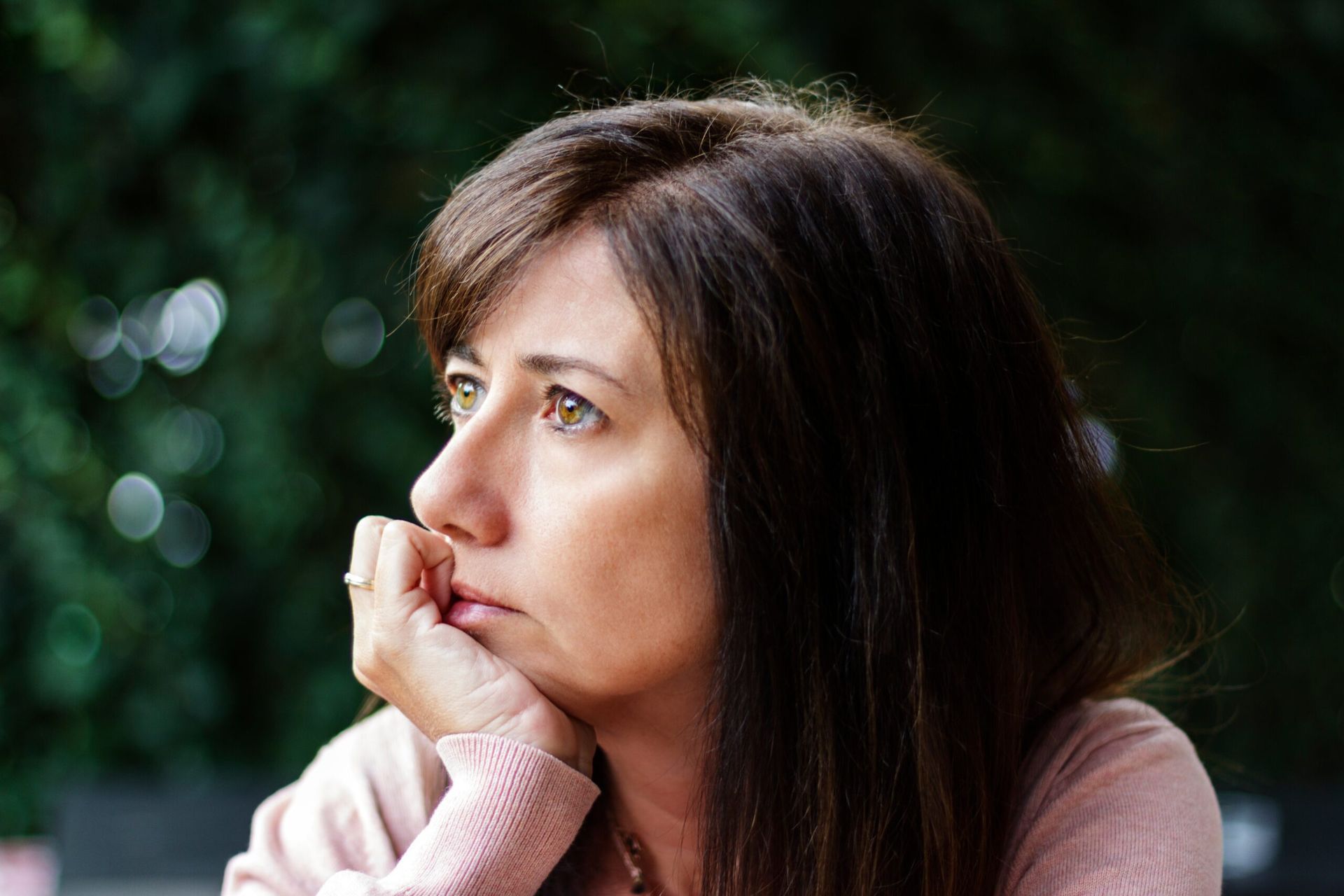 A woman is sitting at a table with her hand on her chin.