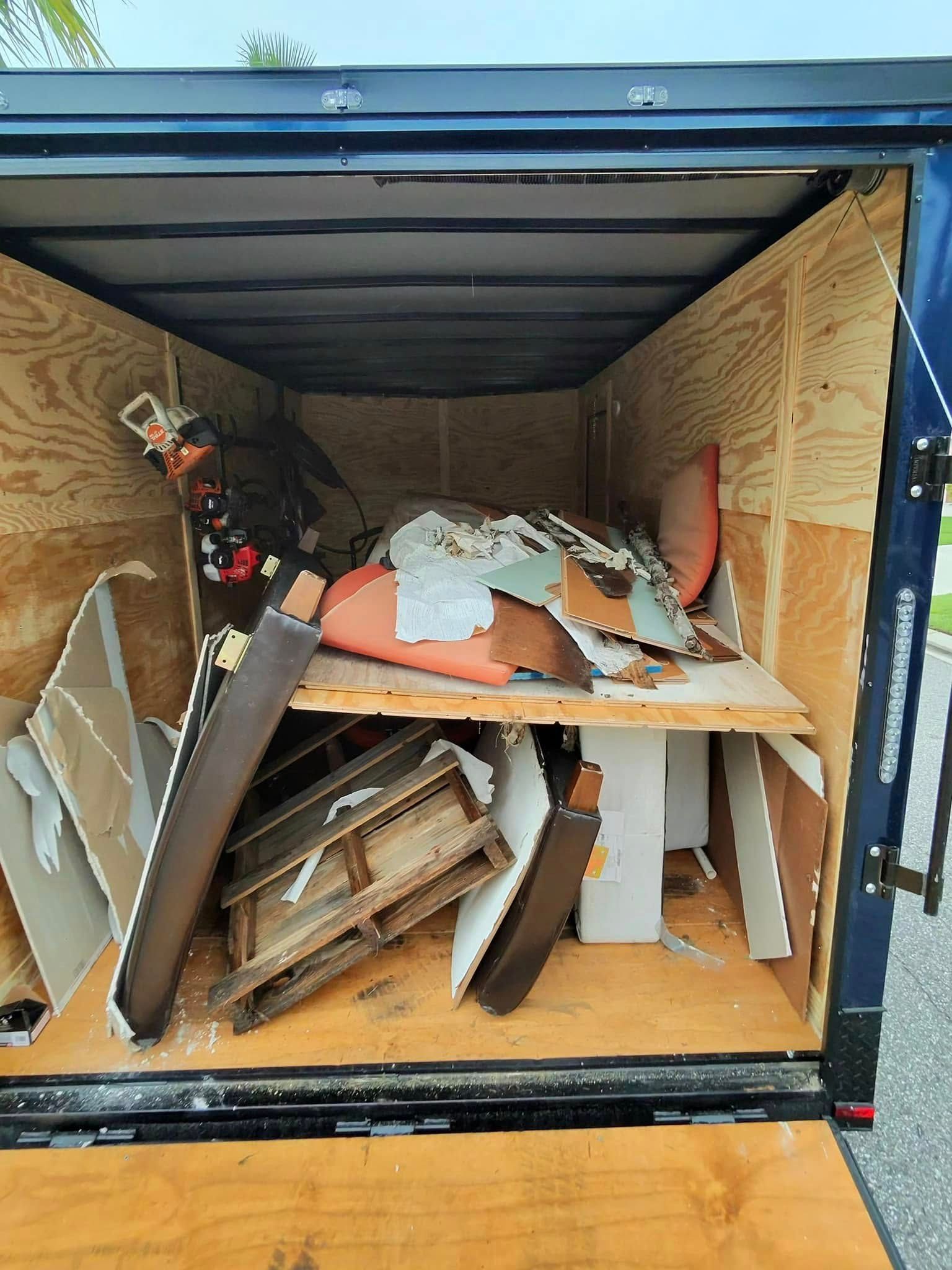 Inside of a blue trailer filled with construction debris: wood, drywall, and other waste.