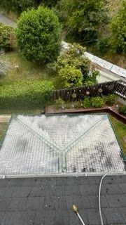 An aerial view of a roof being cleaned with a pressure washer.