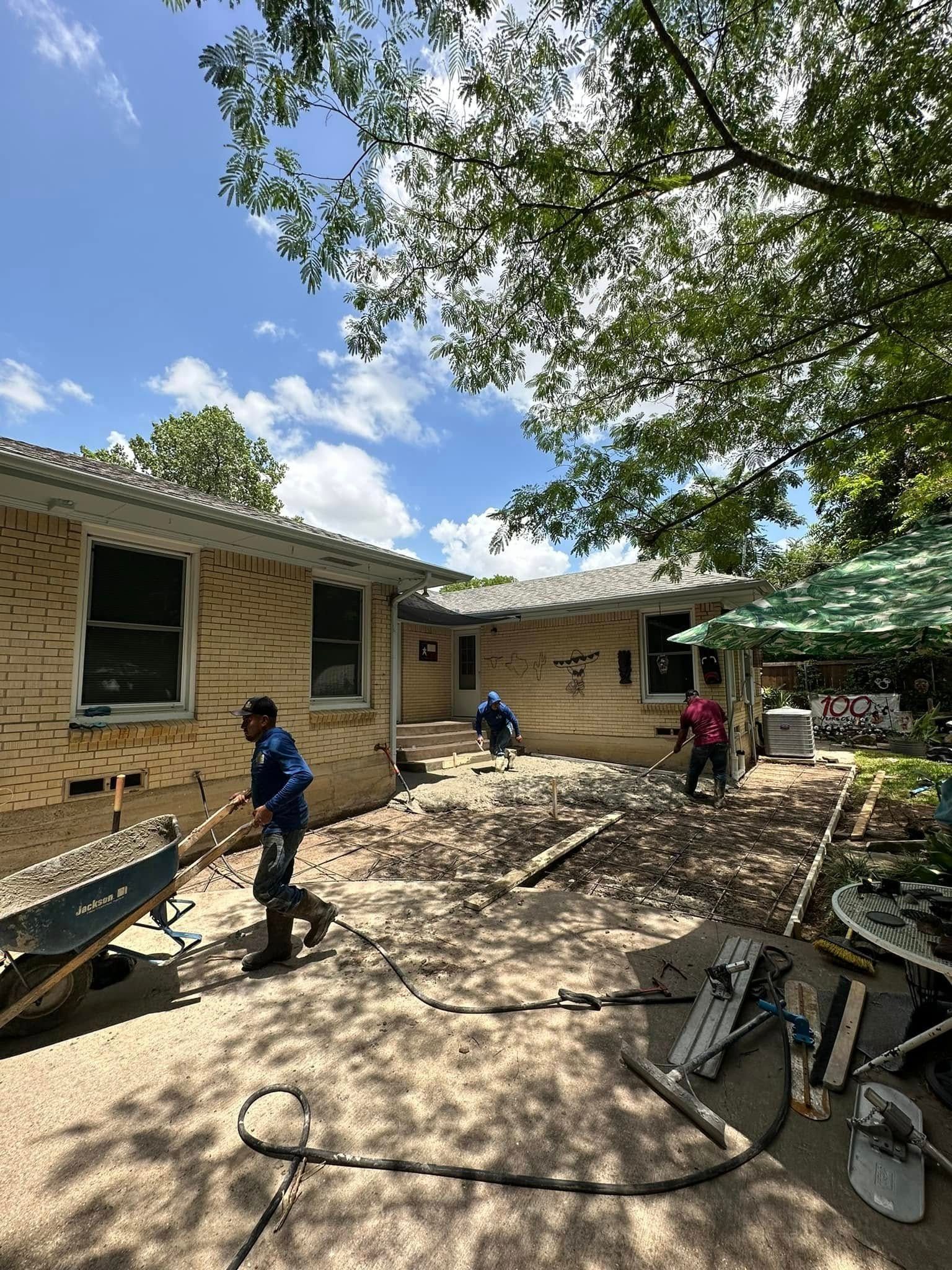 A man is pushing a wheelbarrow in front of a house.