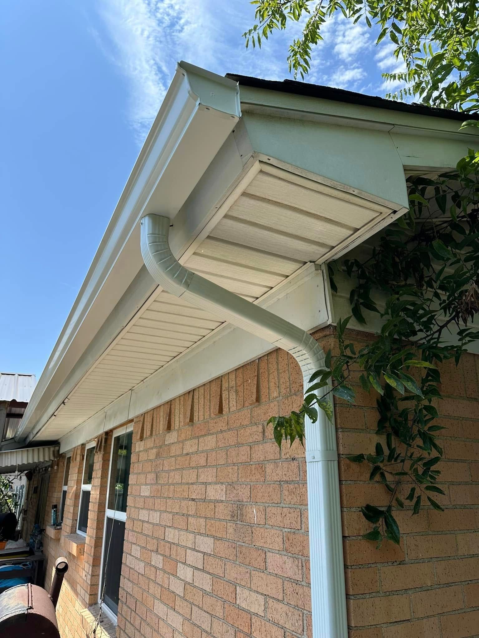 A brick house with a white gutter on the side of it.