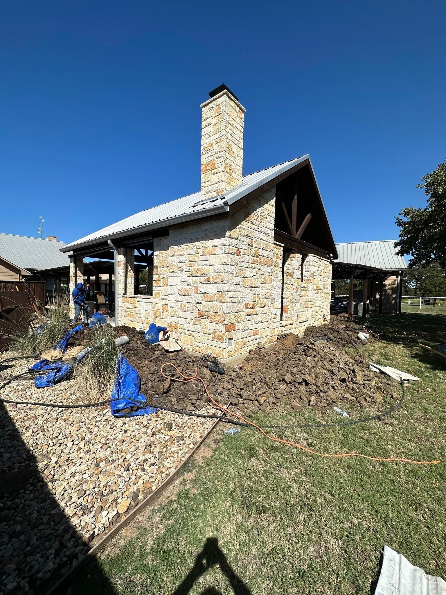 A large pile of dirt is in front of a stone house.