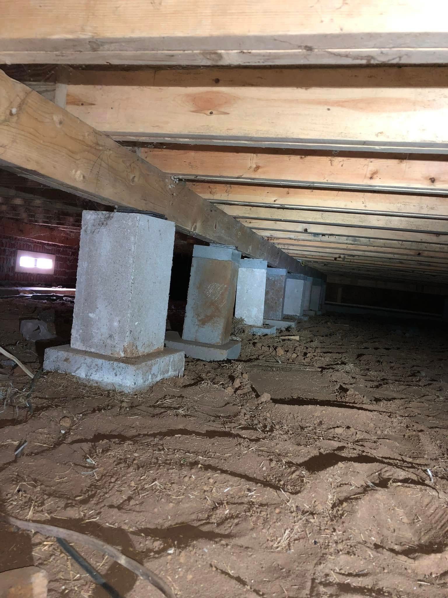 A crawl space under a house with concrete pillars