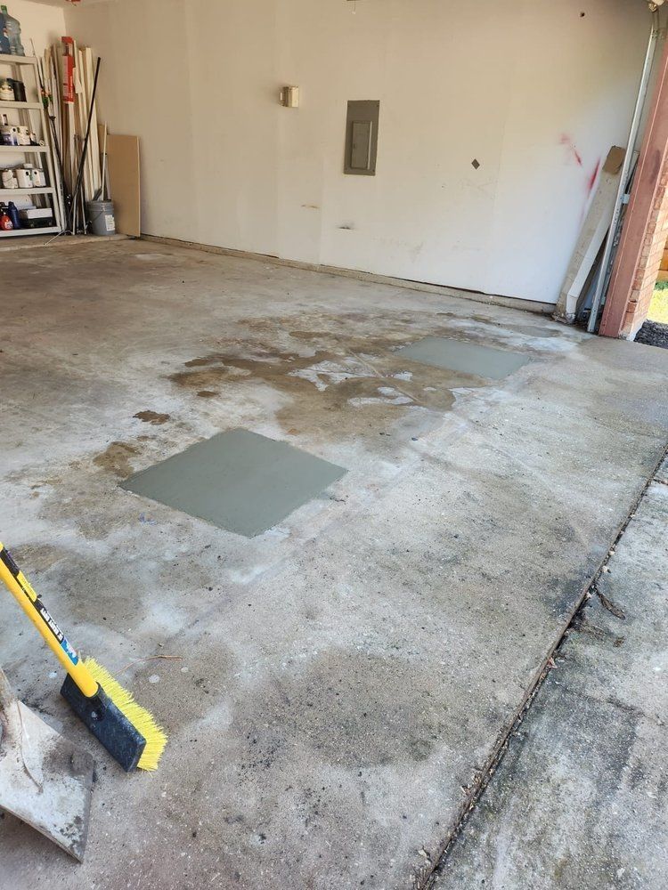 A broom is sitting on the floor of a garage.