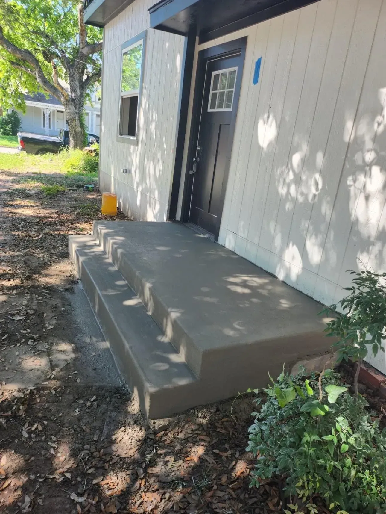 A concrete porch with stairs leading to the front door of a house.