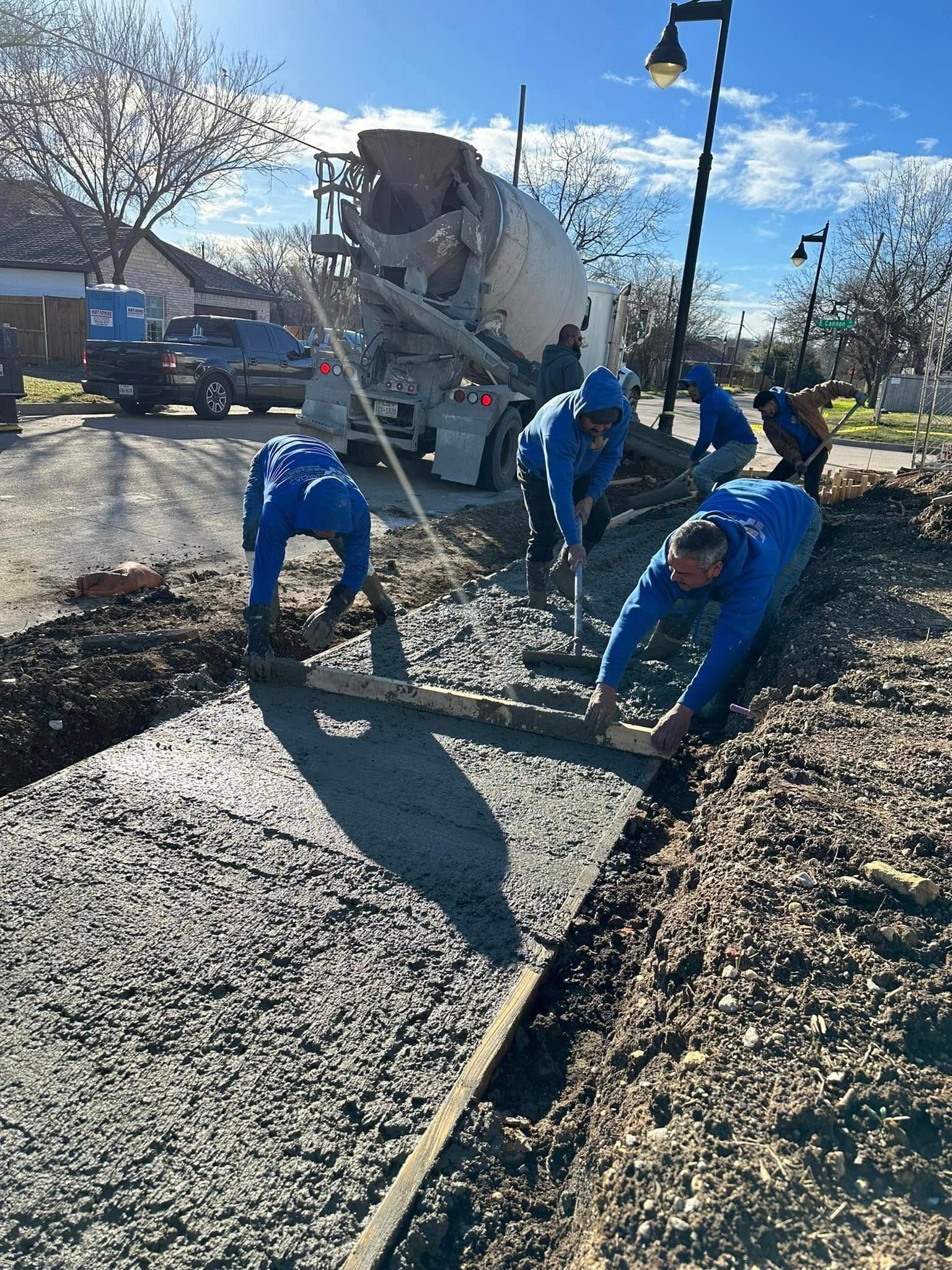 A group of construction workers are working on a concrete driveway.
