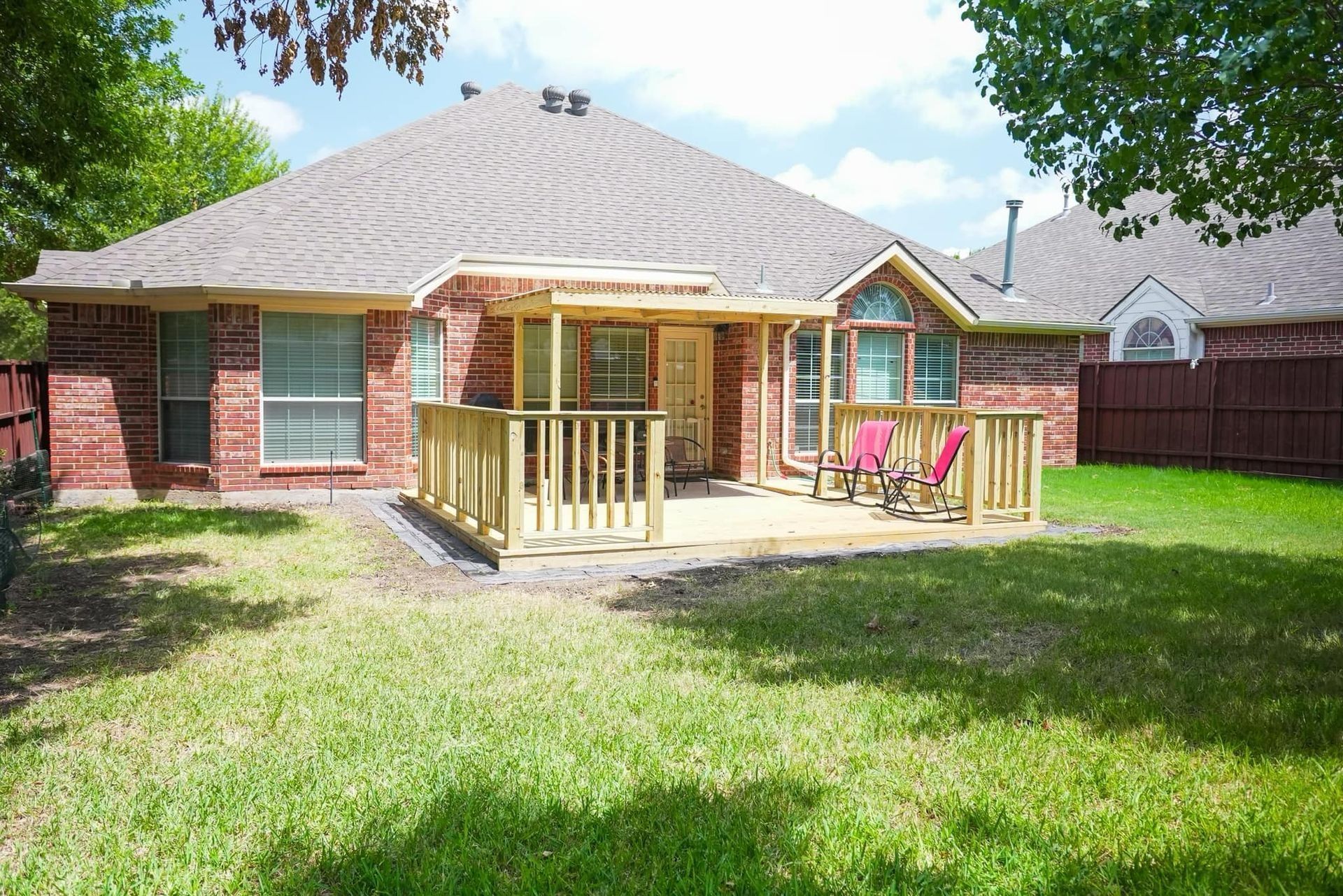 A brick house with a wooden deck in the backyard.