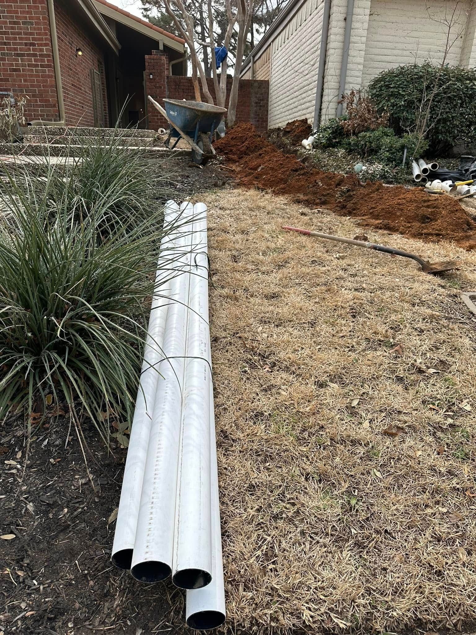 A stack of white pipes sitting on top of a pile of dirt in a yard.