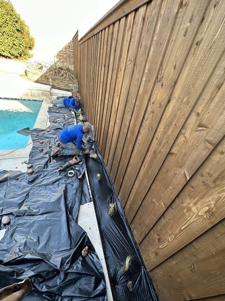 A man is working on a wooden fence next to a pool.