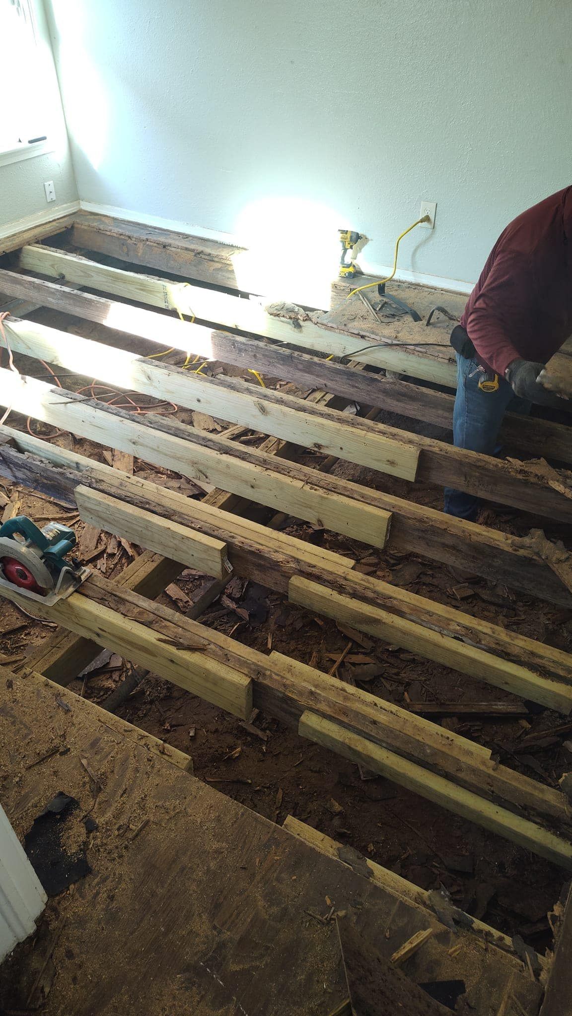 A person is working on a wooden floor in a room.