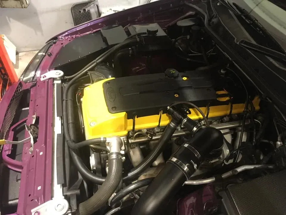 Clean engine bay showing yellow valve cover and fuel injection components on a Ford inline 6-cylinder engine— Chris Bale Automotive in Toronto, NSW
