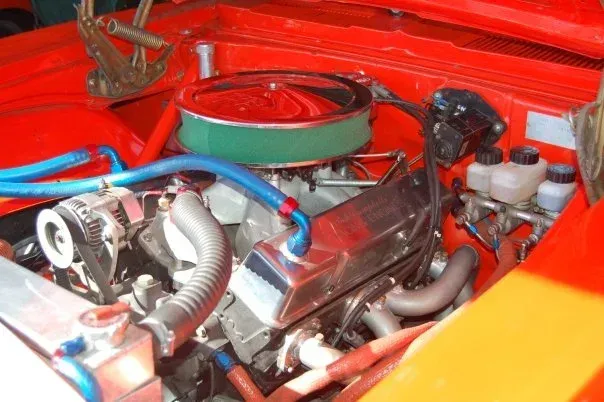 Restored classic V8 engine with chrome covers and round air filter in a red engine bay— Chris Bale Automotive in Toronto, NSW