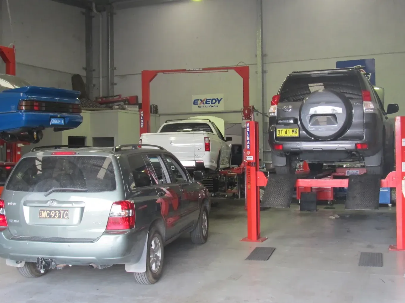 Multiple vehicles on hoists in a busy automotive workshop.— Chris Bale Automotive in Toronto, NSW