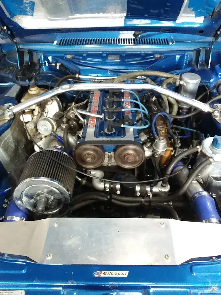 Ford Motorsport engine with dual throttle bodies, blue plug leads, and custom piping — Chris Bale Automotive in Toronto, NSW